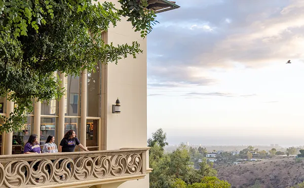 A large building on the left with a tree covered landscape stretching into the distance on the right