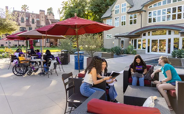 A group of students studying in front of a multi-story building on MSMU's Doheny Campus