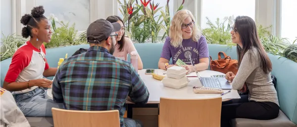 Five students talking around a table