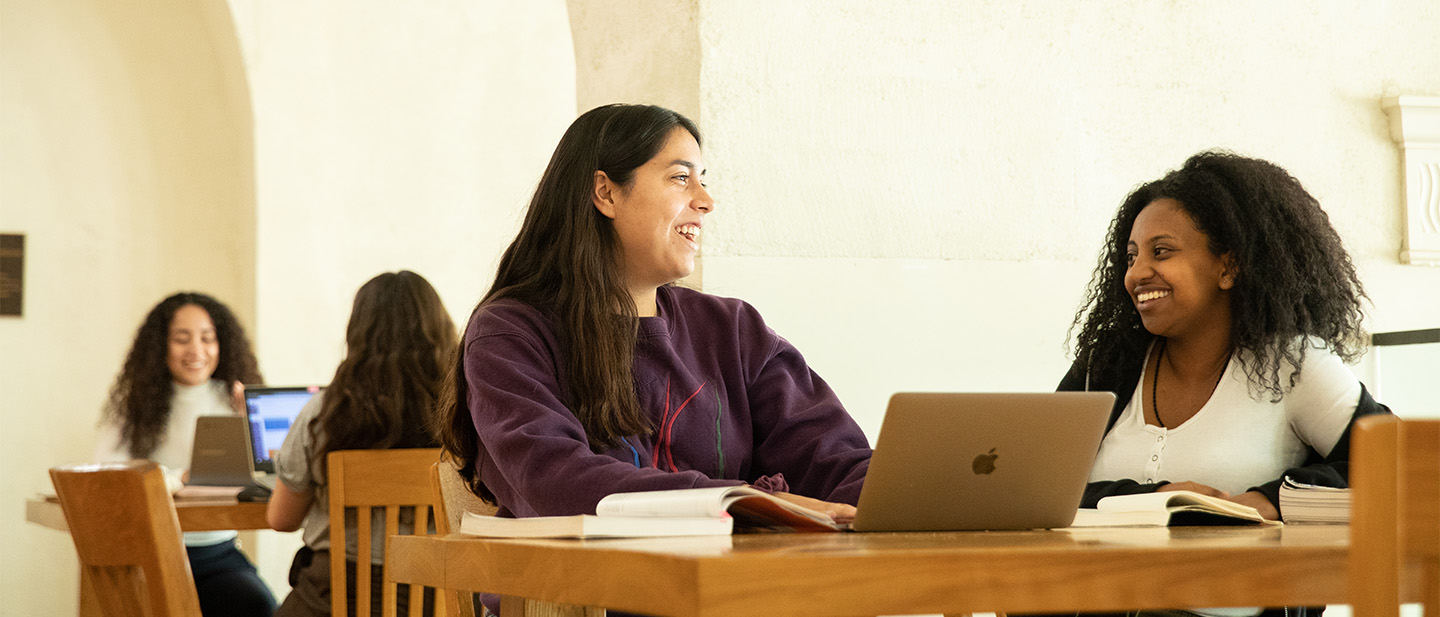 Two students sitting at a table and talking.