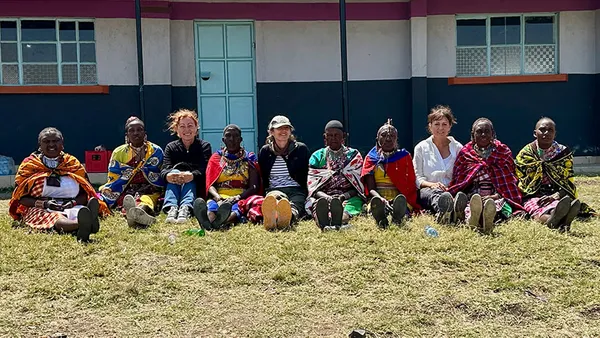 faculty sitting in the grass with children in Kenya