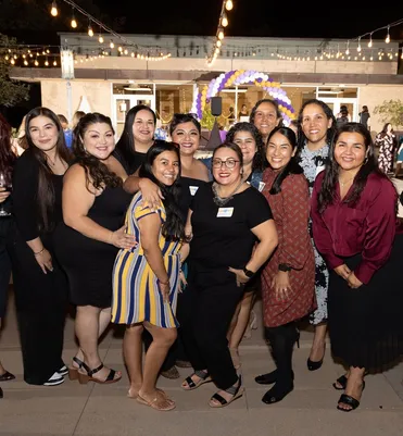 group of women smiling together at a night event on doheny campus