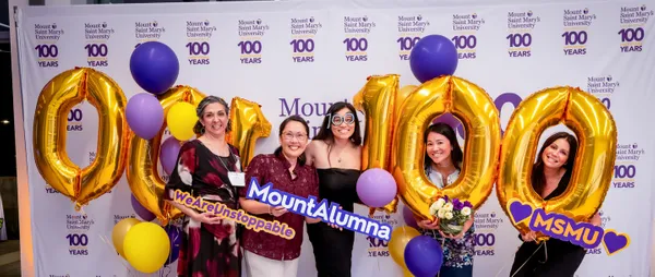 group of female alums posing with props on a photo wall