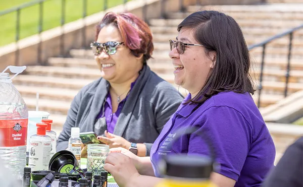 Two people sitting at an event booth outside