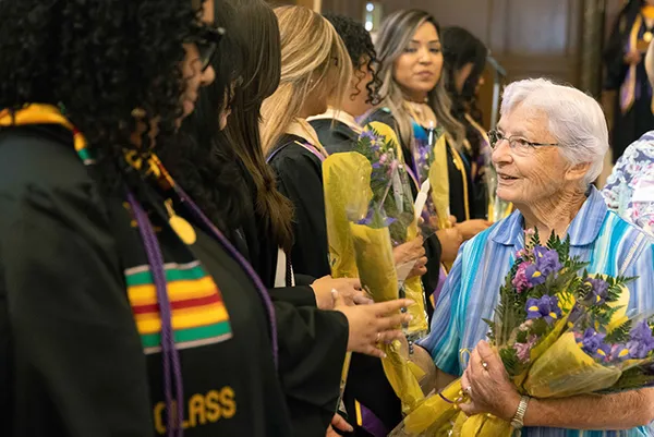 An older woman handing flowers to MSMU Graduates