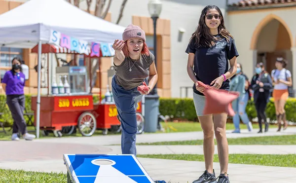 Two students playing cornhole on the lawn