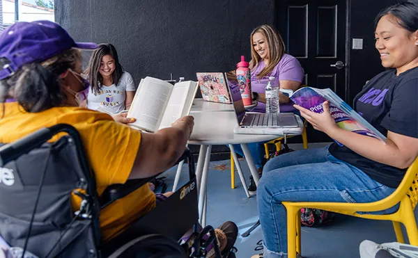 A group of four students reading around a table outside