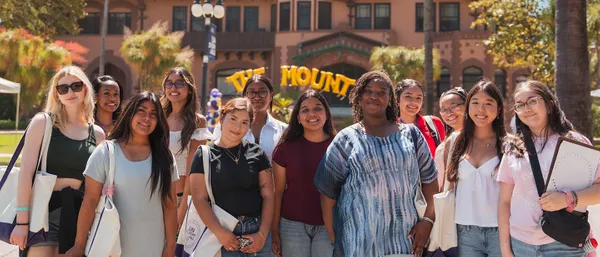student smiling outside at the doheny campus in front of the doheny mansion