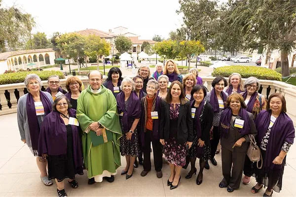 group of alumnae, president, and priest smiling on Chalon campus
