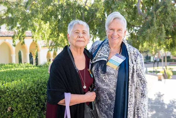 two alumnae standing together on campus smiling