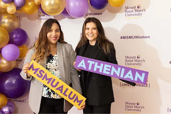two alums smiling with MSMU signs