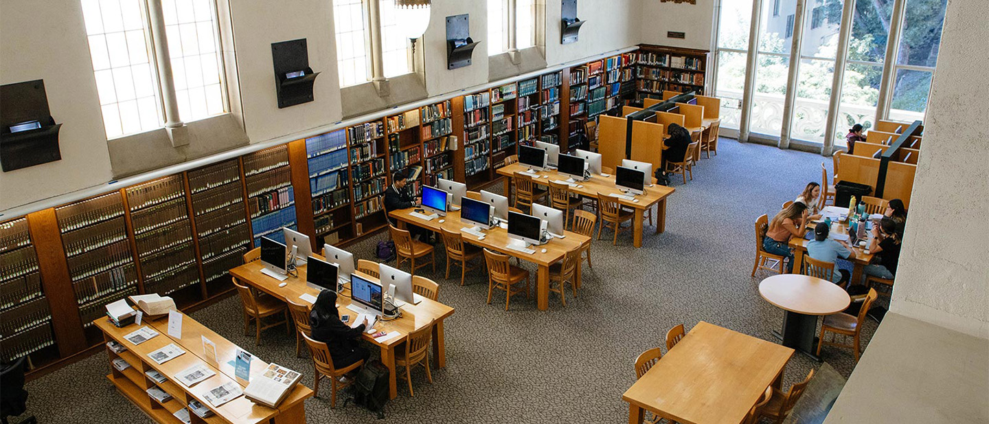 An overhead image of computer desks and bookshelves in a large library hall.