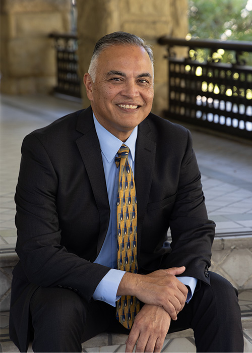Fred Ramirez, dean of education, sitting on steps in suit