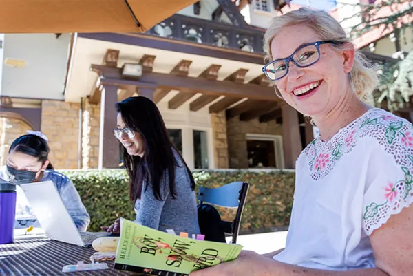 students sitting at table reading and smiling