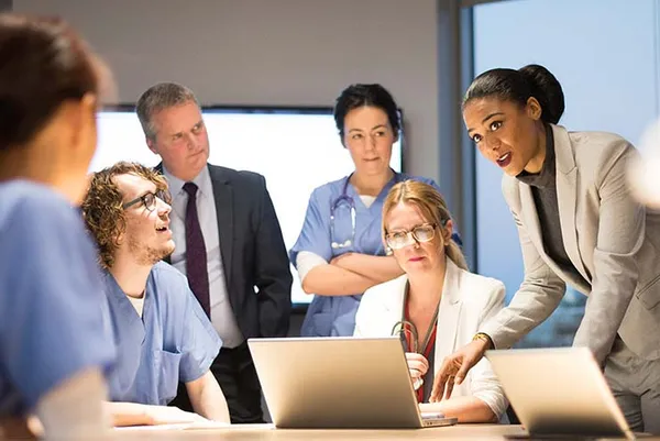 group of medical professionals working together at a table with laptops out.
