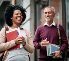 two adults holding class materials smiling