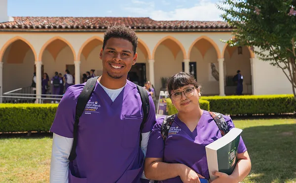 Two MSMU students smiling on Chalon campus holding books